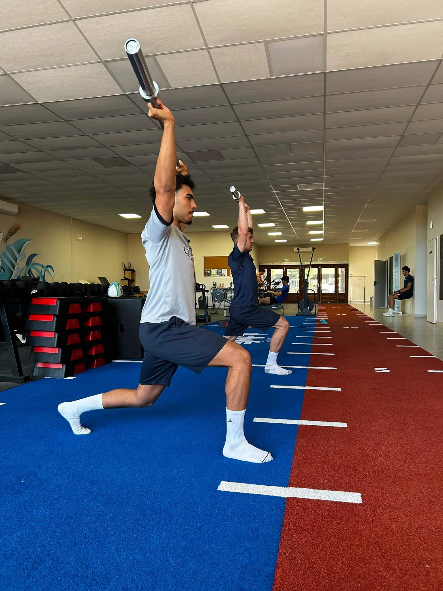 Deux sportifs travaillent les fentes en préparation physique collective